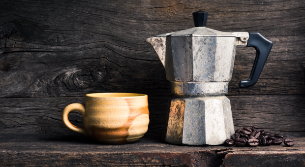 cafetera italiana y una taza de café con granos de café tostados en un  recipiente de madera 10841144 Foto de stock en Vecteezy