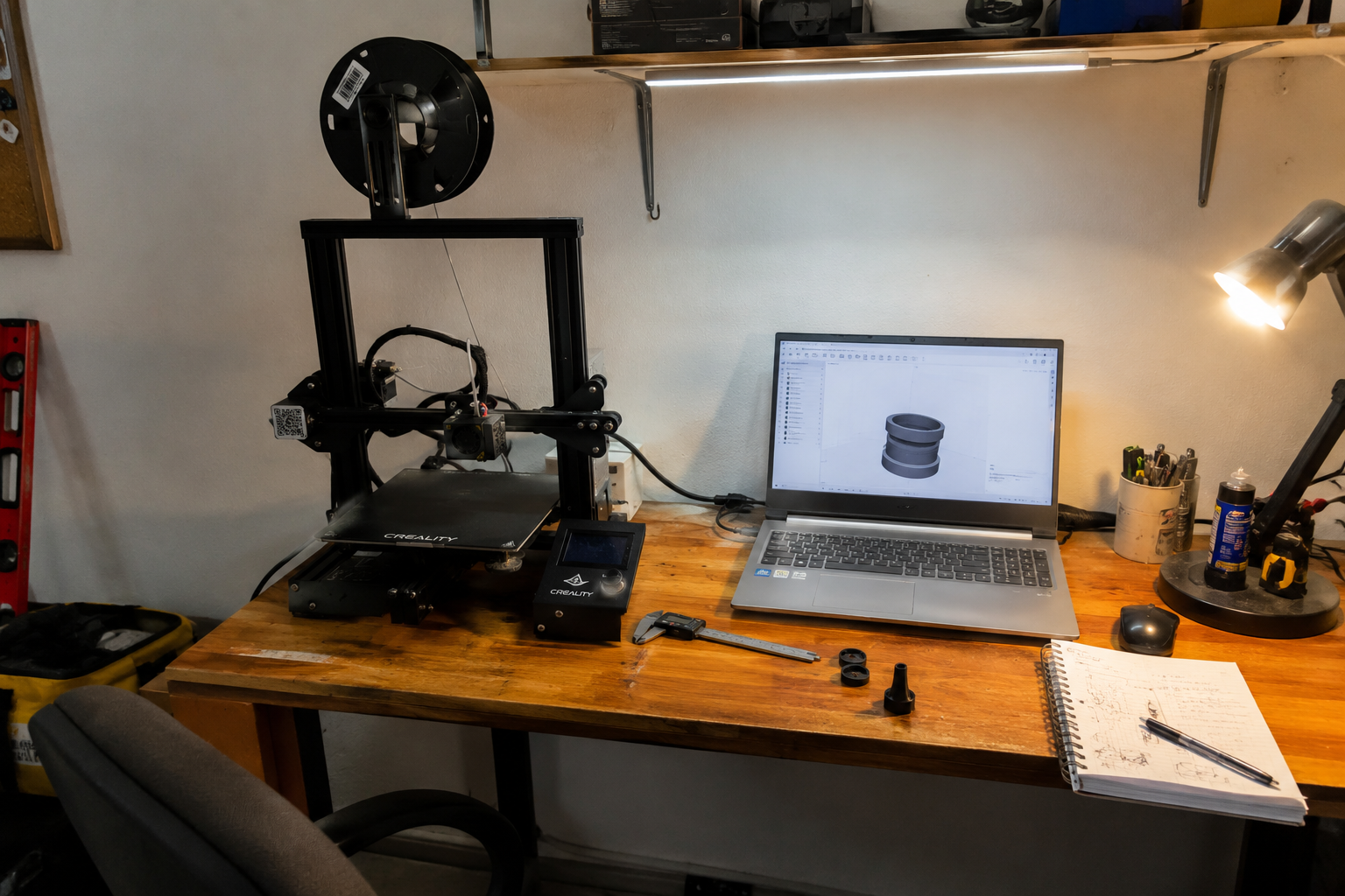 rimer taller de Daniel con una impresora 3D Ender-3 V2, computadora, herramientas, filamentos y piezas impresas sobre una mesa.